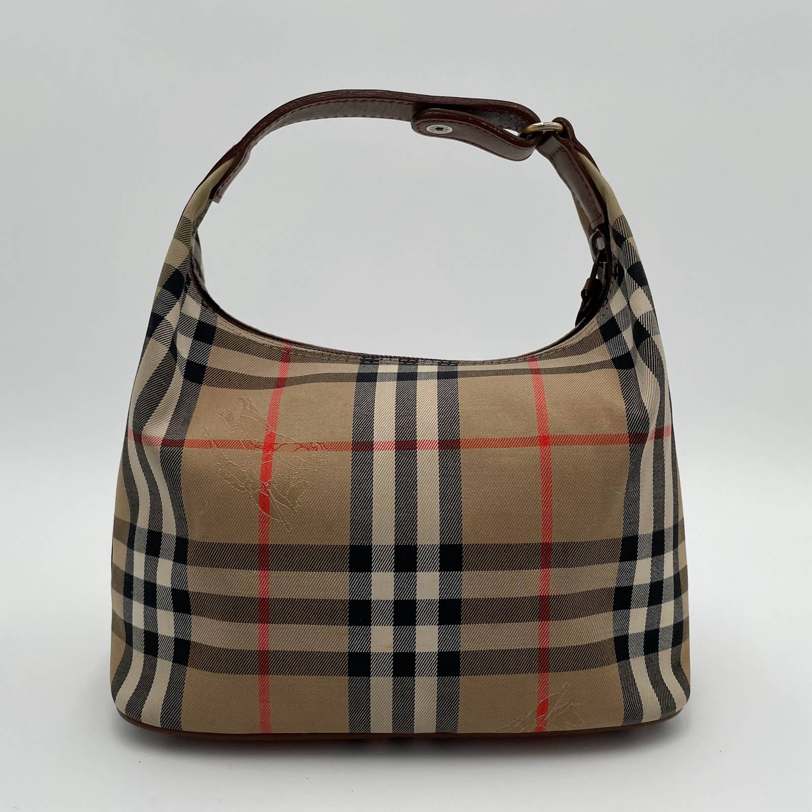 A small handbag with a beige, black, and red checkered pattern resembling the Burberry Vintage House Check Bag. Featuring a short brown strap, canvas with leather trim, and a zip top. The bag has a curved, structured shape and is displayed against a plain white background by Burberry.