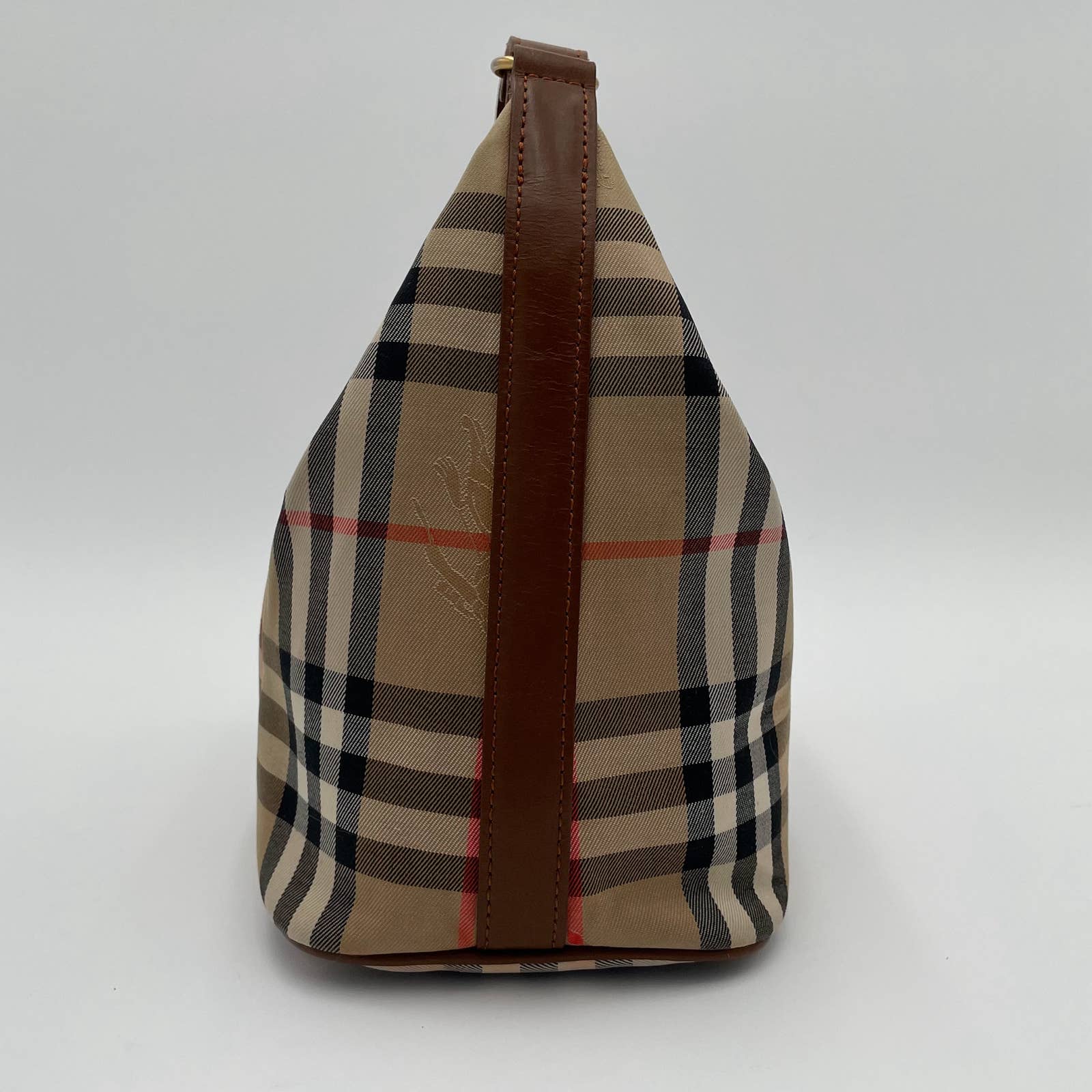 A side view of a stylish beige tote bag with a classic plaid pattern featuring black, white, and red lines. The Burberry Vintage House Check Bag has a brown leather strap running vertically from top to bottom and is crafted from canvas with leather trim. The background is plain white.