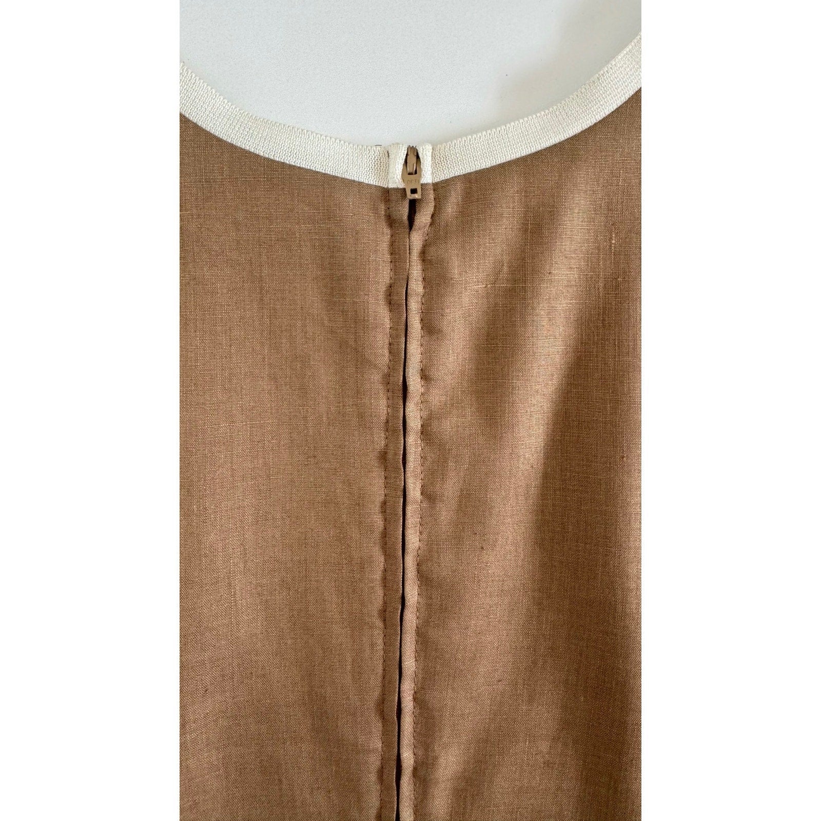 A close-up view of the back of a beige Valentino Miss V Linen Tank Top made of a textured, 100% linen fabric. The garment has a visible central seam with a concealed zipper closure. The fabric is homogenous in color, and the small metallic zipper pull sits just below a white lining at the collar, reminiscent of vintage Valentino Miss V craftsmanship.