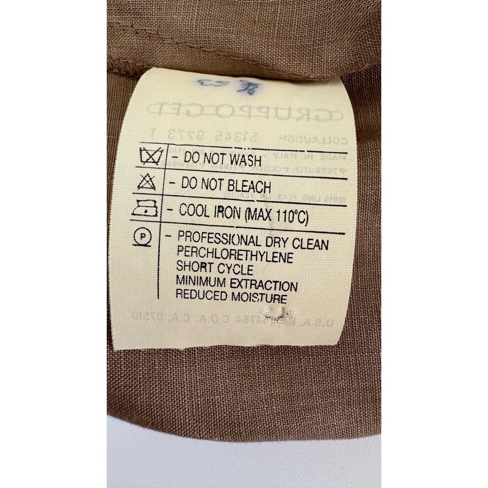 Close-up image of a clothing care label on a Valentino Miss V Linen Tank Top. Instructions: Do not wash, do not bleach, cool iron (max 110°C), professional dry clean with perchloroethylene, short cycle, minimum extraction, reduced moisture. The label is on a brown 100% linen fabric.