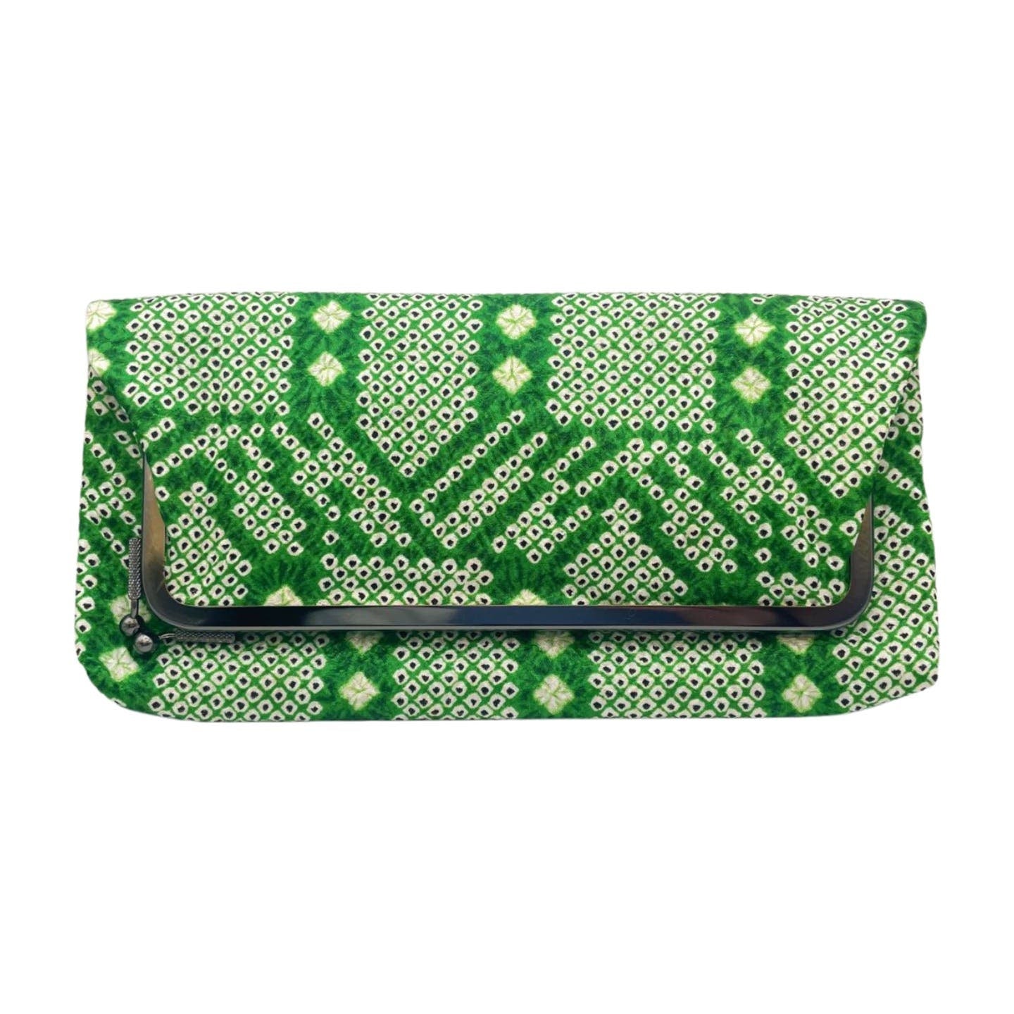 The Vintage 1970's Green Clutch features a vibrant green, white, and black geometric pattern on crinkled silk. It has a flap closure with a small black bar detail on the front. The intricate design includes alternating diamond and triangle shapes, complemented by a soft cotton lining inside.