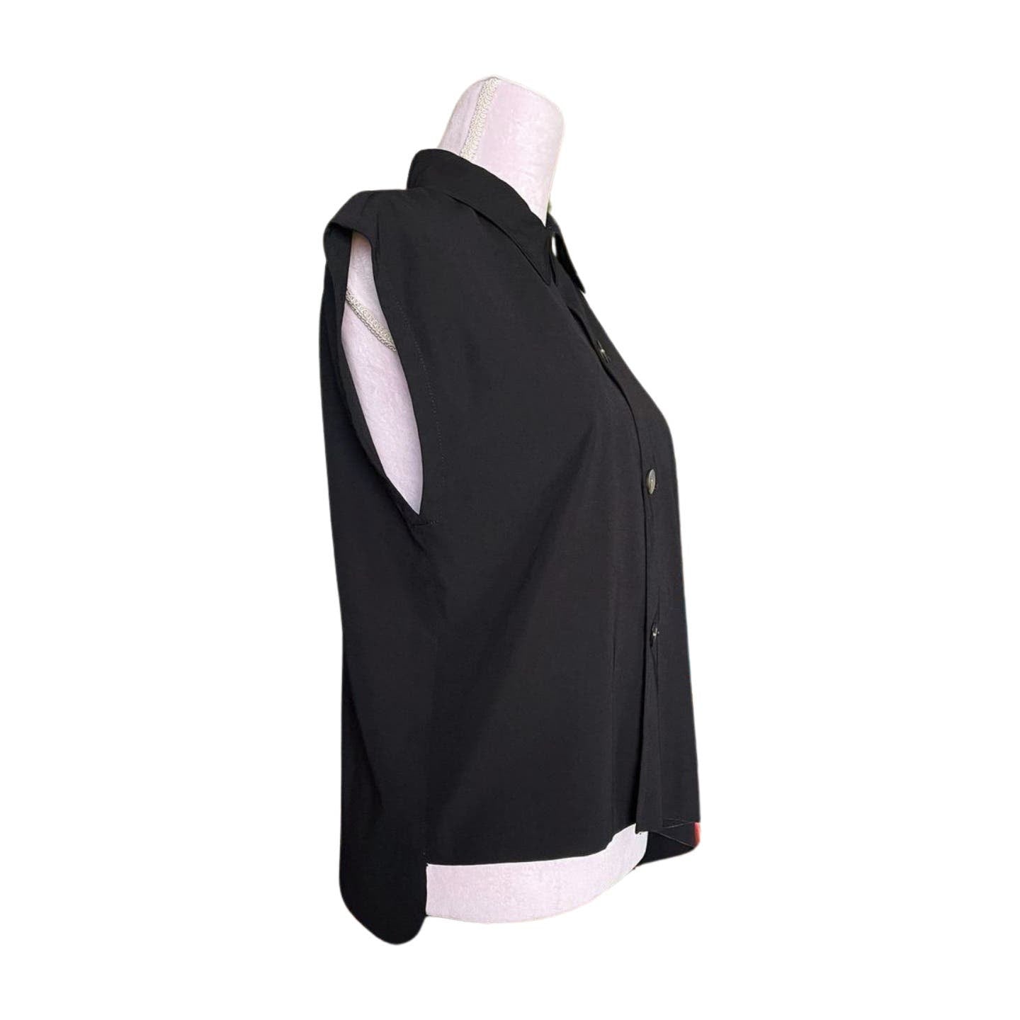 Side view of a black sleeveless blouse on a mannequin. The blouse has a collar and is buttoned down the front. Made from light, flowy polyester, it is suitable for casual or semi-formal wear. The mannequin is white and has no visible head or arms, giving it a minimalist Comme des Garcons vibe. This item is the Vintage 1992 Comme des Garçons Asymmetric Top by Comme des Garçons.