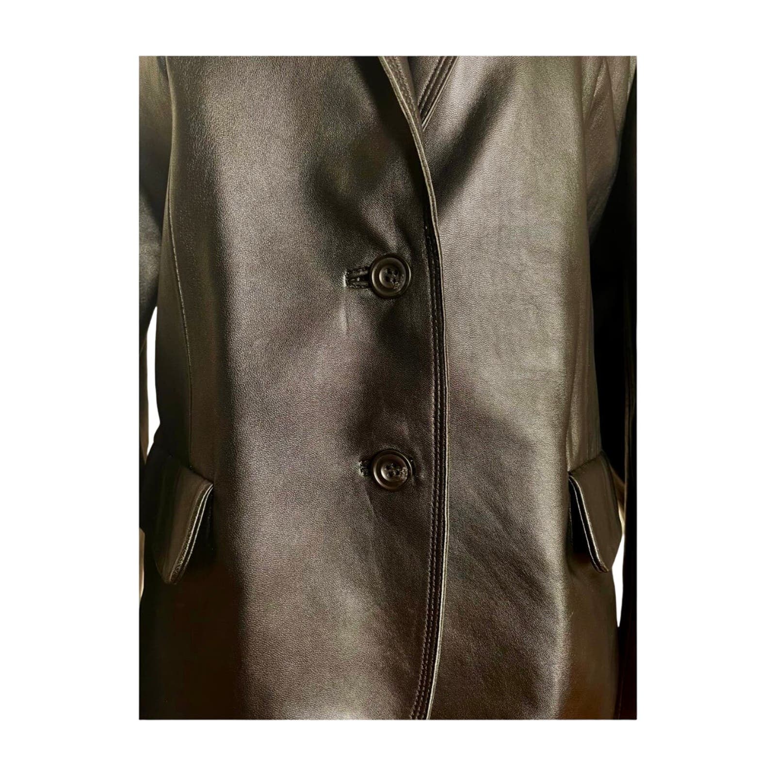 Close-up image of a Vintage Balmain Black Leather Blazer, highlighting the shiny texture and the details of two front buttons and side pockets. The blazer, showing a luxurious polyester lining, appears formal and well-fitted. Perfect for any occasion after professional cleaning.