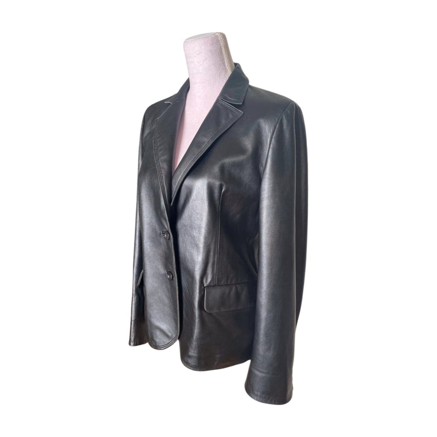 A Vintage Balmain Black Leather Blazer displayed on a mannequin. The blazer features a classic design with notch lapels, a single-breasted front with two buttons, and two front pockets with flaps. The blazer, which has a polyester lining, is showcased from a slight angle and requires professional cleaning.